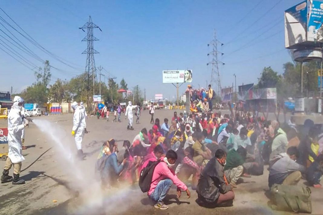 Trabalhadores indianos são pulverizados com desinfetantes, enquanto são forçados a ficarem sentados